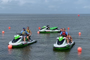 a group of people riding on the back of a boat in the water