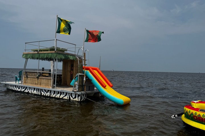 Floating barge with slide and flags on a lake.